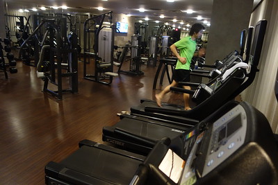 een man in een groen Tshirt is aan het fitnessen op een loopmachine