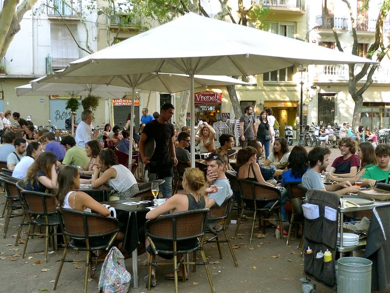 mensen zitten aan tafeltjes op een terras van een café in Nederland of België