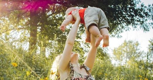 een moeder die haar baby omhoogtilt om het begrip "ondersteunen" te illustreren