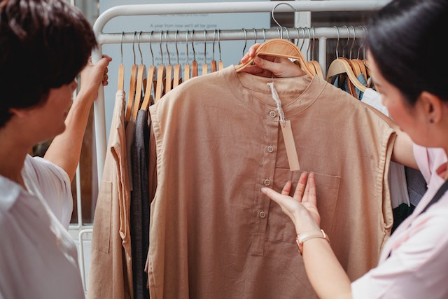 twee vrouwen kijken in een winkel naar een overhemp en bespreken de prijs-kwaliteitsverhouding